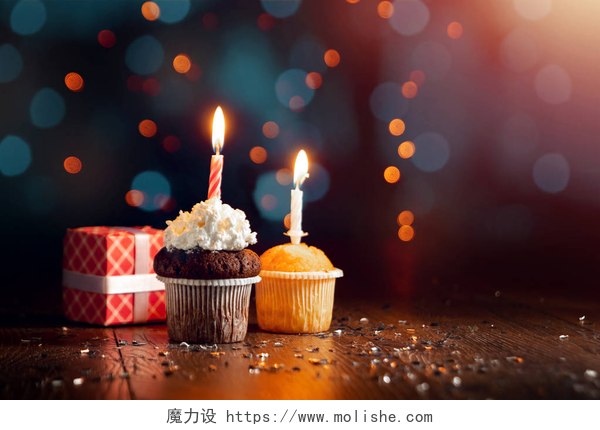 在暗色背景下的两小块蛋糕和木质的桌子还有一个红色的礼盒创意背景, 小蛋糕与蜡烛, 美丽的 bokeh。生日快乐。目前。度假卡的概念, 传单, 背景。复制空间